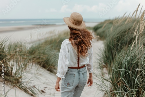 Back view of a woman enjoying a peaceful walk along a sandy beach.