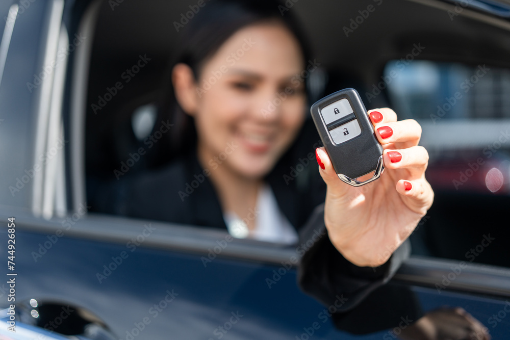 Young beautiful asian business women in suit getting new car showing car key. she very happy and excited in hand holding car key. Smiling female driving vehicle on the road city on a bright day Young beautiful asian business women in suit getting new car showing car key. she very happy and excited in hand holding car key. Smiling female driving vehicle on the road city on a bright day