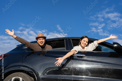 Young asian couple travel by car on a bright day beautiful blue sky sticking their head outta the windshield. They was happy along the way trip. safety driving car. Travel tourism © Chanakon