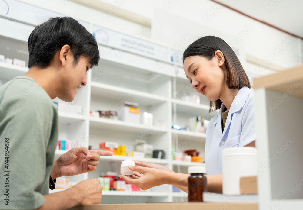 Pharmacist recommends medicines to customers.Taking the questions of medication. Asian female pharmacist giving prescription medications to customers at drugstore shelves. Pharmacist recommends medicines to customers.Taking the questions of medication. Asian female pharmacist giving prescription medications to customers at drugstore shelves.