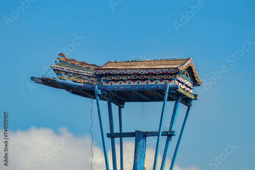 a traditional wooden dove house on a pillar against a cloudy blue sky background