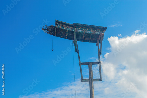 a traditional wooden dove house on a pillar against a cloudy blue sky background