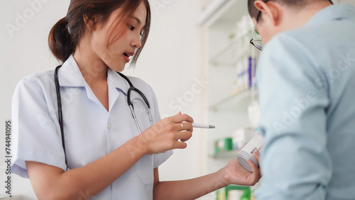 Medicine and health concept  Female pharmacist hold pill bottle to explaining medication for client