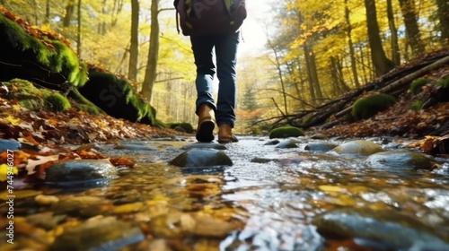 Low angle view of hiker crossing the forest stream in autumn