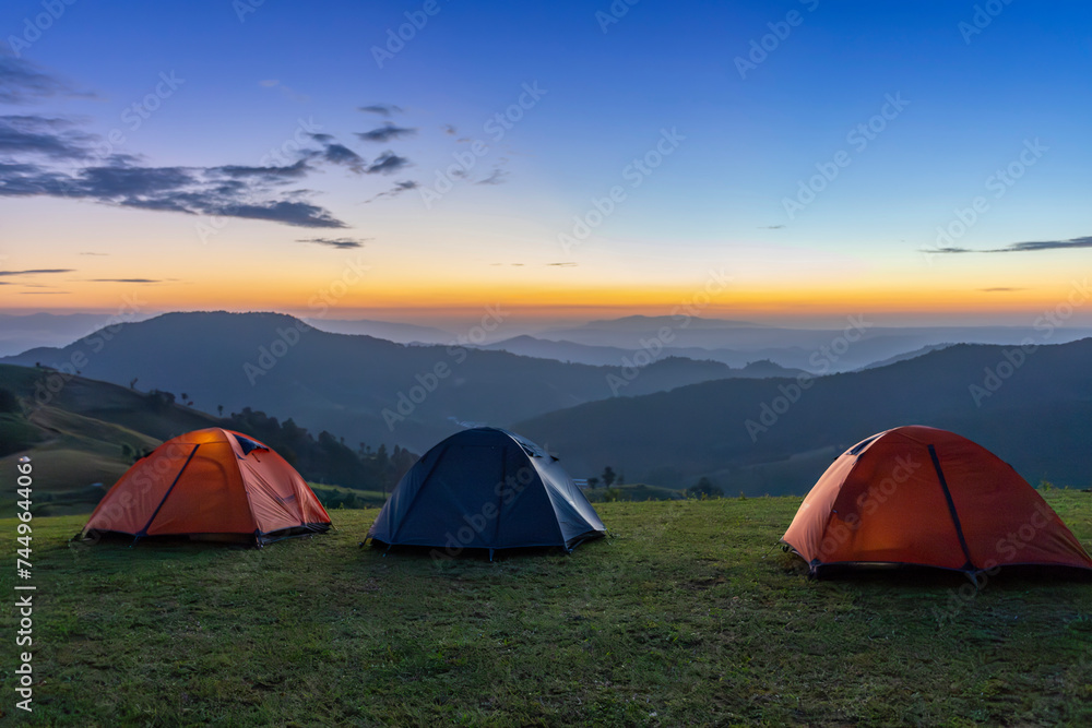 Group of adventurer tents during overnight camping site at the beautiful scenic sunset view point over layer of mountain for outdoor adventure vacation travel concept