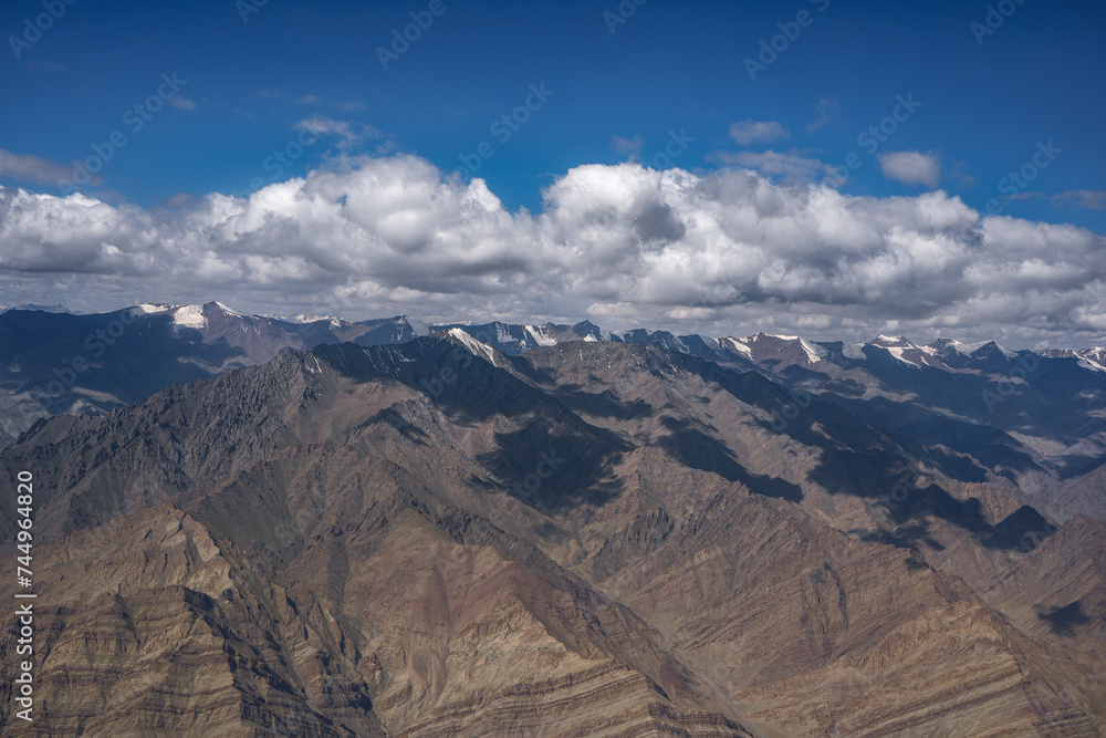 Eye Level view of rainbow colored mountain with patches of cloud shadow and snow on the mountains