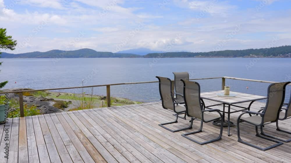 Establishing shot of balcony or veranda in a modern house with nice ocean and mountain view with blue sky and white clouds. Day time June 2023. ProRes 422 HQ.