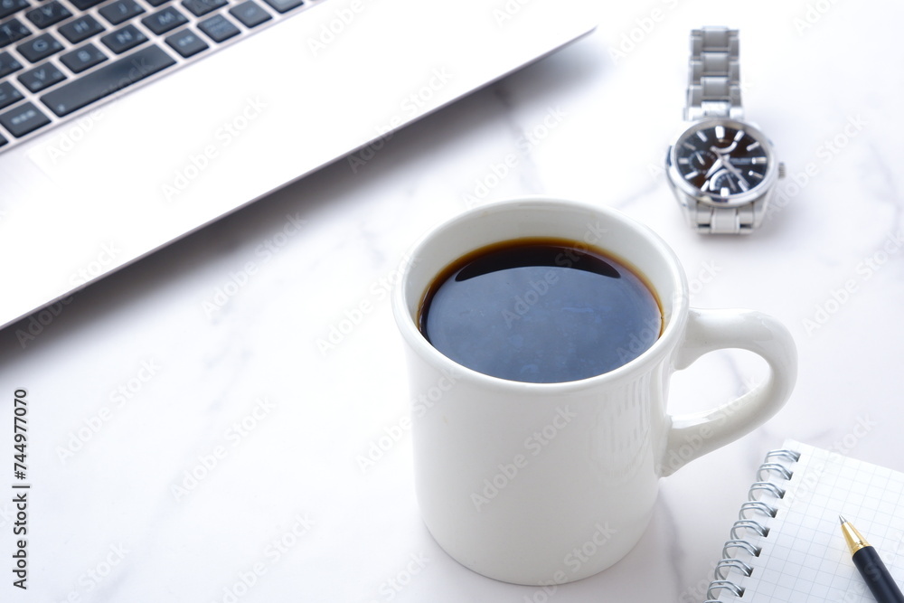 コーヒーを飲みながらノートパソコンでデスクワークをしているイメージ コーヒーを飲みながらノートパソコンでデスクワークをしているイメージ