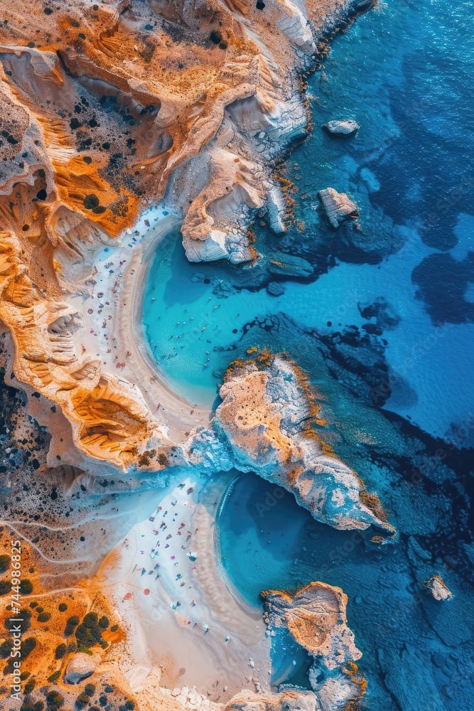 Aerial view of a stunning beach with turquoise waters, surrounded by rugged cliffs.