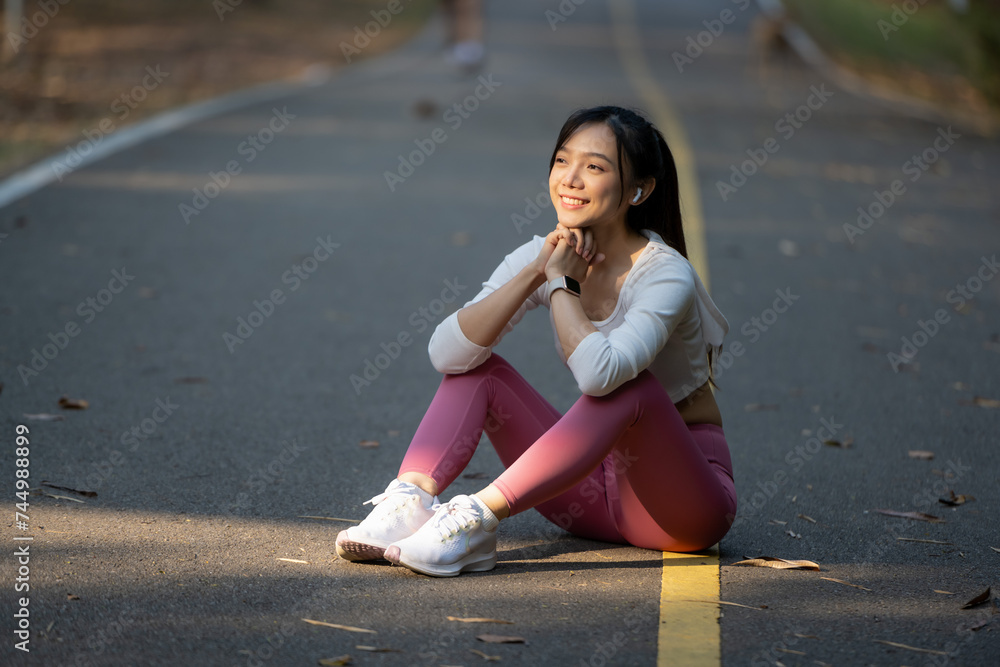 A young woman sits on the road to rest after jogging. A young woman sits on the road to rest after jogging.