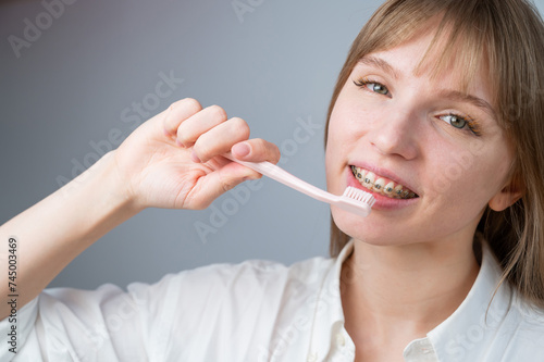 Portrait of a caucasian woman with braces on her teeth holding a toothbrush.