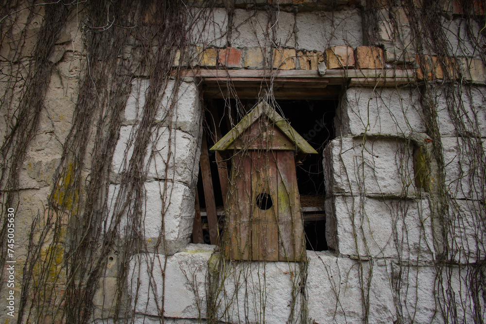 An old wooden birdhouse in a window of a crumbling building