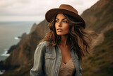 Stylish woman with hat enjoying scenic coastal view. Adventure and travel.