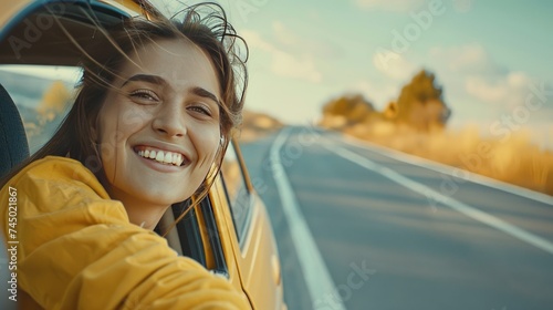 Young attractive smiling woman driving a car with the wind in her hair.