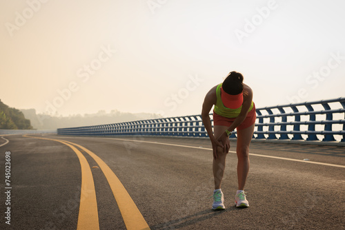 Running sport injury female runner touching her knee