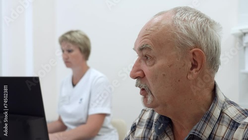 Portrait of an old man patient talking to doctor with female nurse behind. Clip. Concept of public health services. photo