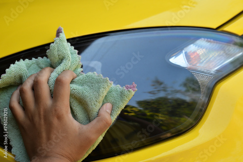 Hand wiping cleaning the car headlight after washing carcare. photo