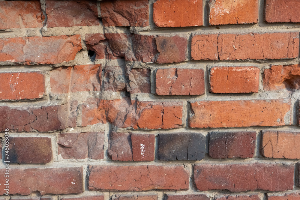 Close-up view of old molded red brick wall covered with craters from military shells, bullets, cracks and scratches. Copy space for your text and decorations. Soft focus. Aftermath of the war theme. Close-up view of old molded red brick wall covered with craters from military shells, bullets, cracks and scratches. Copy space for your text and decorations. Soft focus. Aftermath of the war theme.