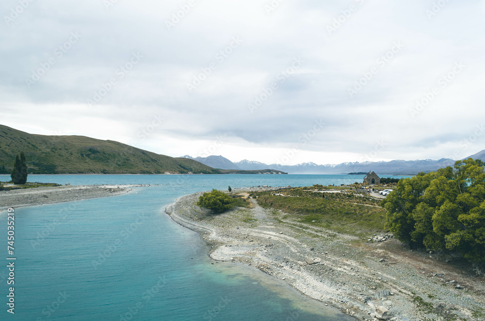 A panoramic view of Lake Tekapo, New Zealand, featuring the scene of a milky turquoise lake and the historic church landmark.