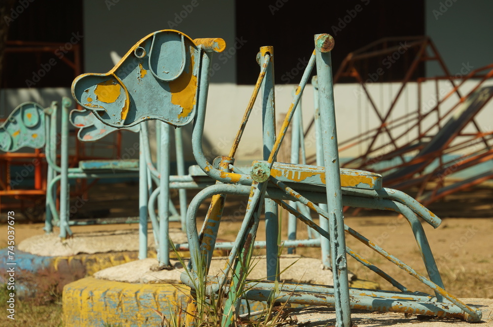 A rocking horse is made in the shape of a dog and made of steel in an outdoor playground in Thailand.