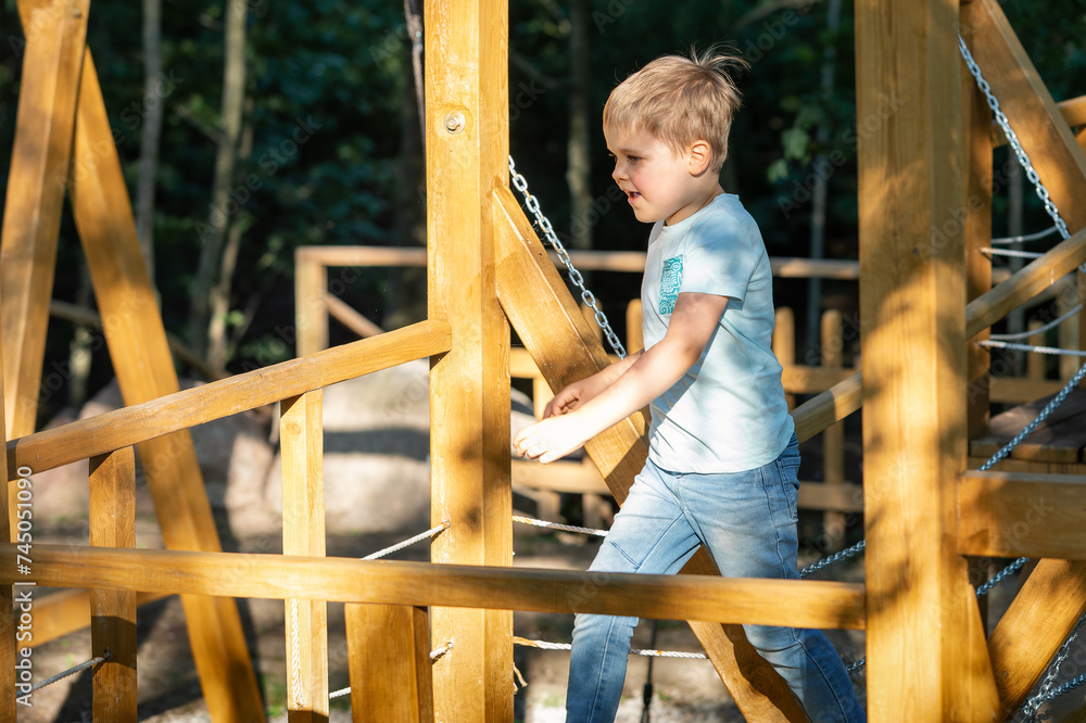 Little happy boy on sunny wooden outdoor playground Little happy boy on sunny wooden outdoor playground