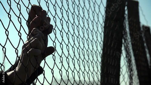 hopeful woman's hands clinging to the border fence: dreaming of freedom, peace