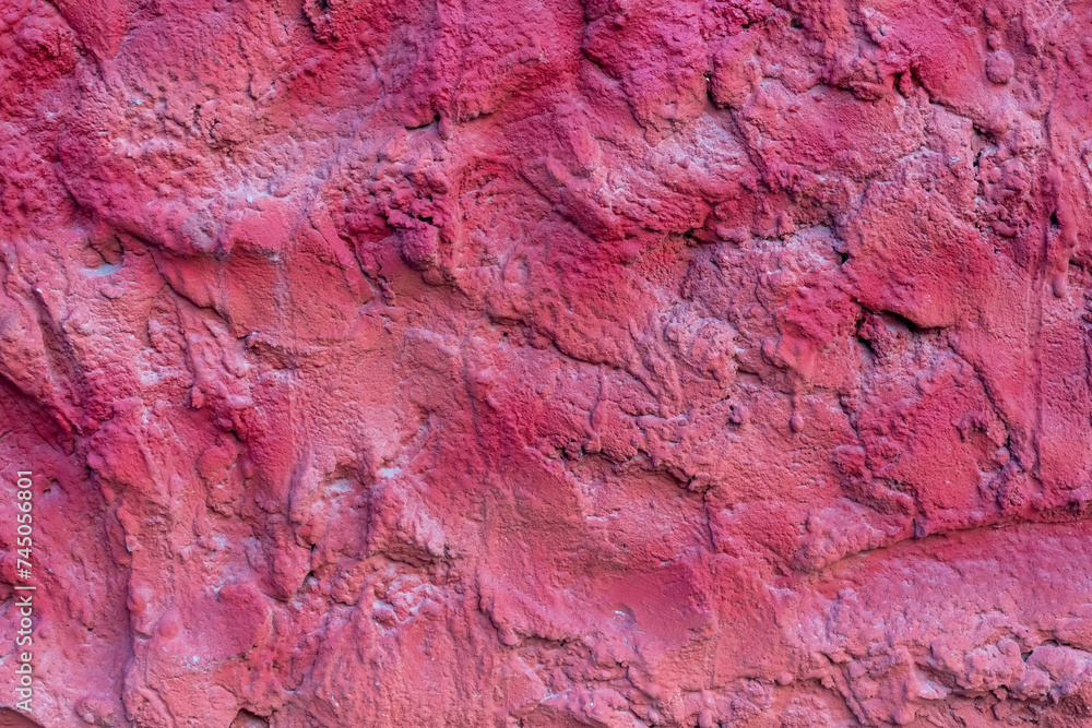 Close-up view of old textured magenta coloured rough plaster wall surface. Copy space for your text or decoration. Soft focus. Colorful construction material background theme.