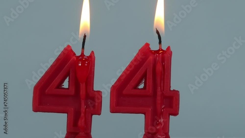close up on timelapse melting a red number forty fourth birthday candle on a white background.
 photo