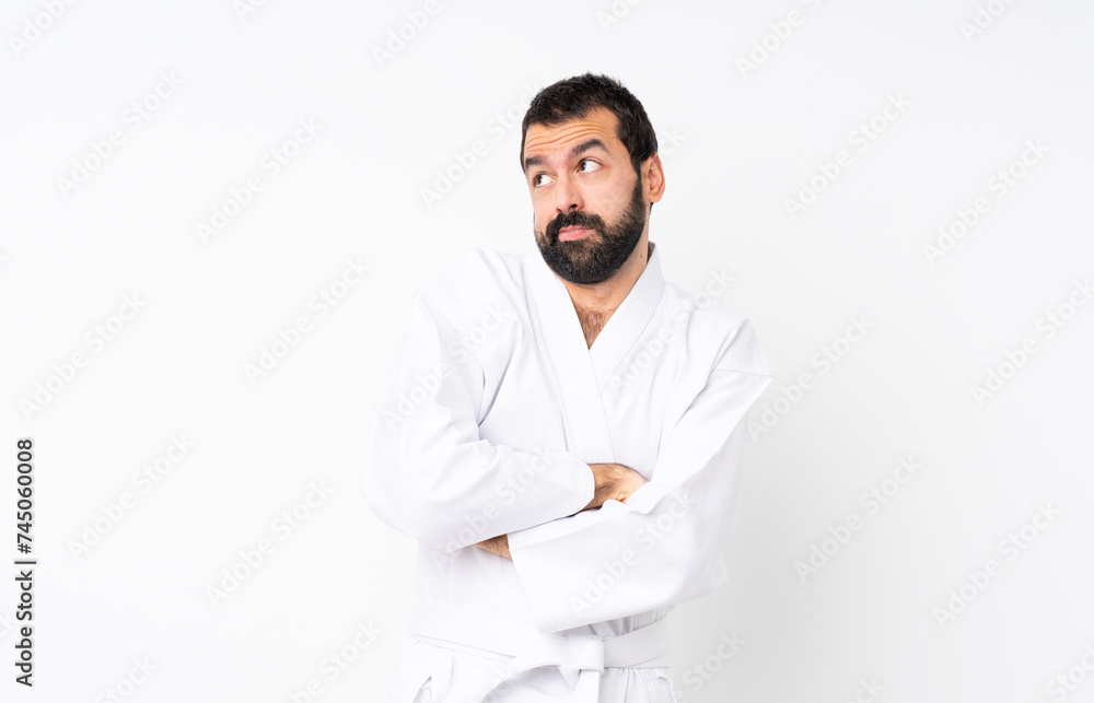 Young man doing karate over isolated white background making doubts gesture while lifting the shoulders Young man doing karate over isolated white background making doubts gesture while lifting the shoulders