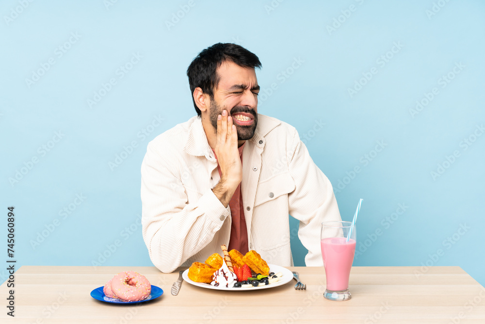 Man at a table having breakfast waffles and a milkshake with toothache Man at a table having breakfast waffles and a milkshake with toothache