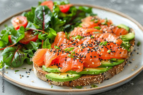 Toast with avocado and salmon with sesame seeds, chard leaves.