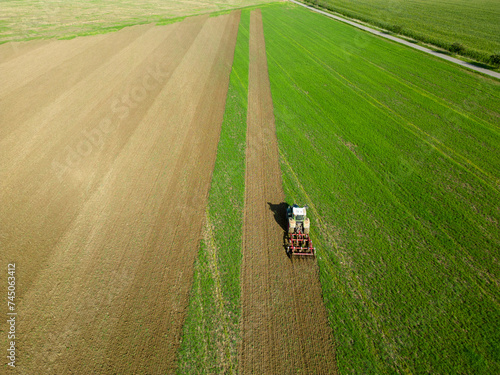 Aerial drone shot of farmer tilling field with his tractor in rural southern Germany