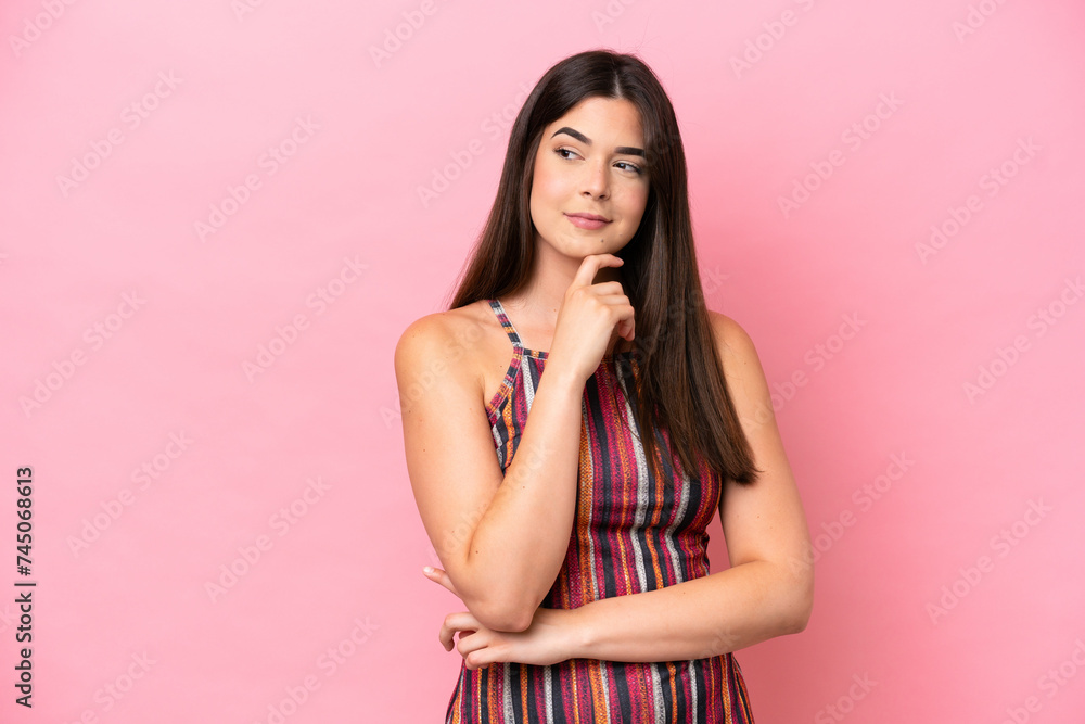 Young Brazilian woman isolated on pink background and looking up Young Brazilian woman isolated on pink background and looking up