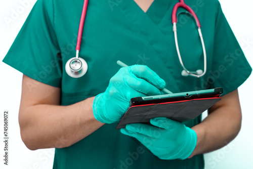 Lekarz w zielonym kitlu pisze na tablecie , wypisuje recepte