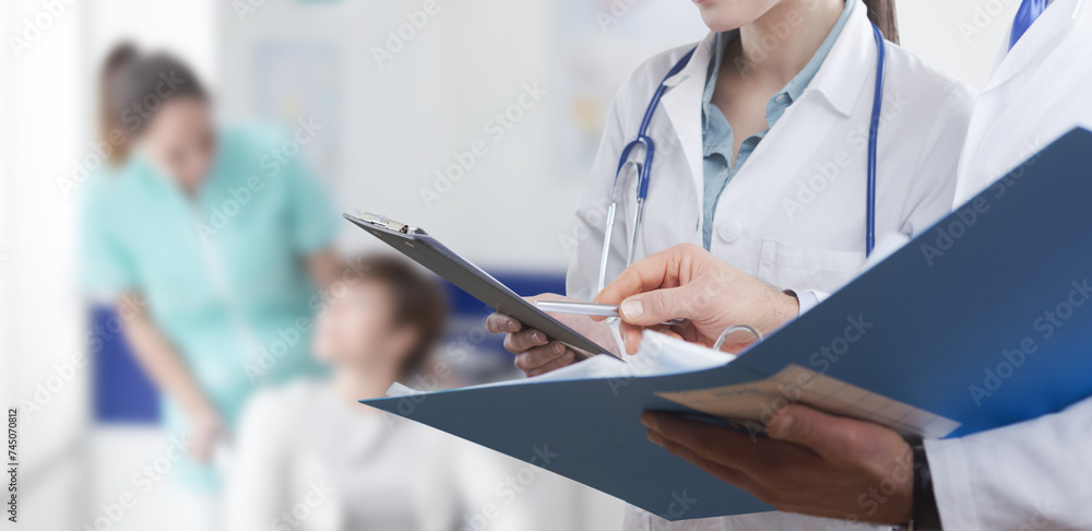 Doctors checking patient's medical records Doctors checking patient's medical records
