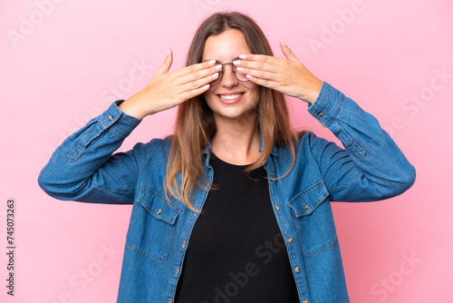 Young caucasian woman isolated on pink background covering eyes by hands and smiling