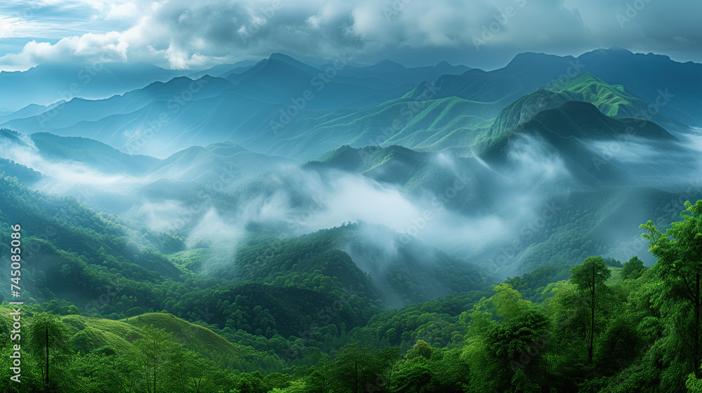 Obraz premium Lush green mountains gracefully enveloped by flowing mist under a cloudy sky.