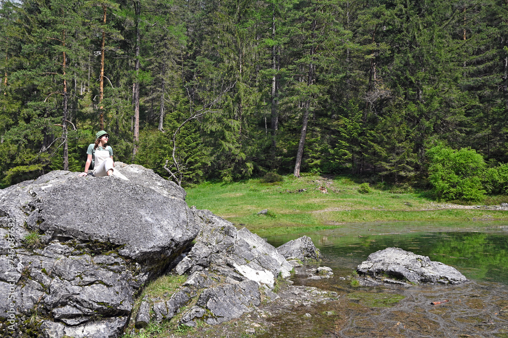 a girl sits on a rock and enjoys nature on Green lake Styria springtime a girl sits on a rock and enjoys nature on Green lake Styria springtime