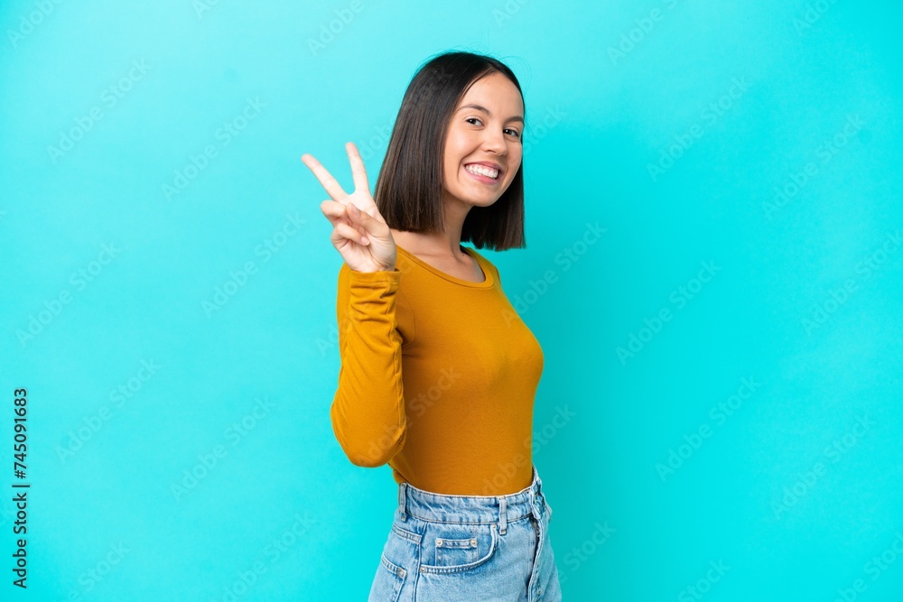 Young caucasian woman isolated on blue background smiling and showing victory sign Young caucasian woman isolated on blue background smiling and showing victory sign