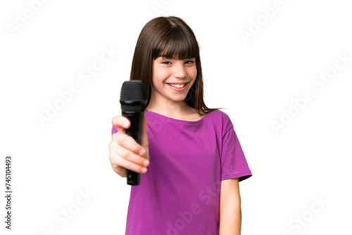 Little singer girl picking up a microphone over isolated background with happy expression