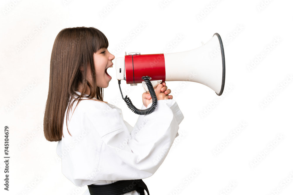 Little Caucasian girl doing karate over isolated background shouting through a megaphone Little Caucasian girl doing karate over isolated background shouting through a megaphone