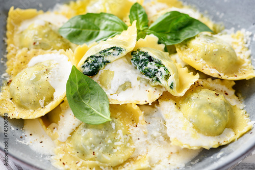 Homemade Ravioli pasta with spinach and ricotta cheese filling with creamy white sauce and grated Parmesan cheese.  photo