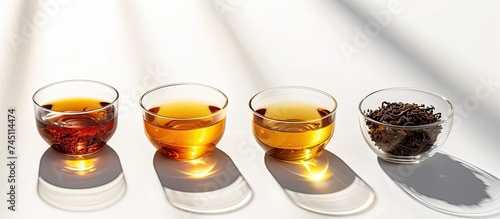 Three identical glasses filled with tea are neatly arranged in a row on a wooden table. The glasses are clear, showcasing the light brown color of the tea.