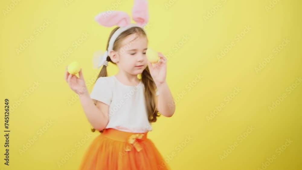 Cute little girl kid wears pink hare ears, holds colored easter eggs grow isolated over yellow background. Look at this decorated Easter eggs! Cute little girl kid wears pink hare ears, holds colored easter eggs grow isolated over yellow background. Look at this decorated Easter eggs!