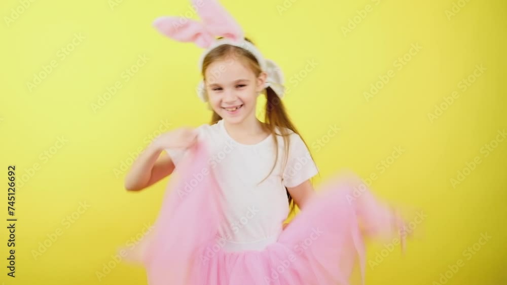 Preteen happy girl in pink bunny ears smiling and dancing isolated on a yellow background. Easter Preteen happy girl in pink bunny ears smiling and dancing isolated on a yellow background. Easter