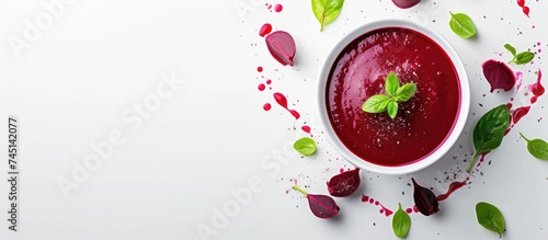 A white bowl is filled with a nutritious vegetarian soup made with beetroot, showcasing a vibrant red liquid topped with fresh green leaves. The combination of colors suggests a healthy and appetizing
