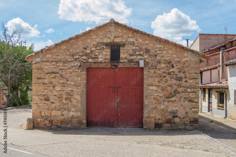 stone barn and red wooden door in a village in Spain stone barn and red wooden door in a village in Spain