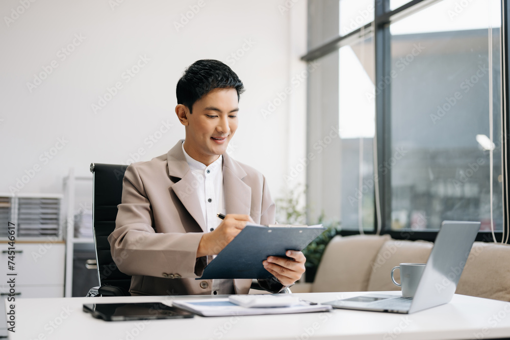 Asian businessman typing laptop and tablet Placed at the table at the office. Asian businessman typing laptop and tablet Placed at the table at the office.
