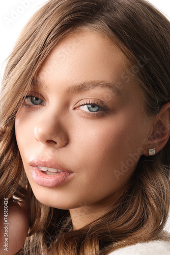 Beautiful young girl with fresh healthy skin. Woman advertise ear-rings. White background. Earrings closeup. Blond european woman with long hair with big lips, pretty smile. Cosmetology, scincare