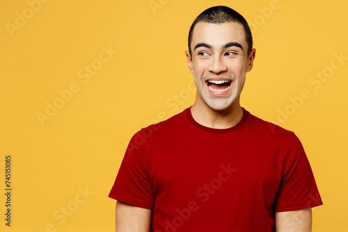 Young surprised smiling shocked happy cheerful middle eastern man he wear red t-shirt casual clothes look aside on area isolated on plain yellow orange background studio portrait. Lifestyle concept. photo